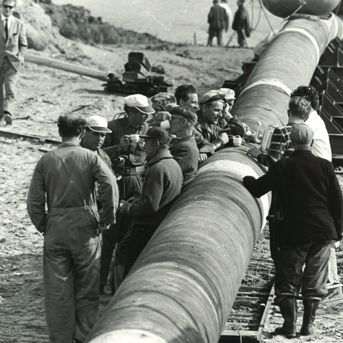 Een groep werkers hebben koffiepauze naast een buis
